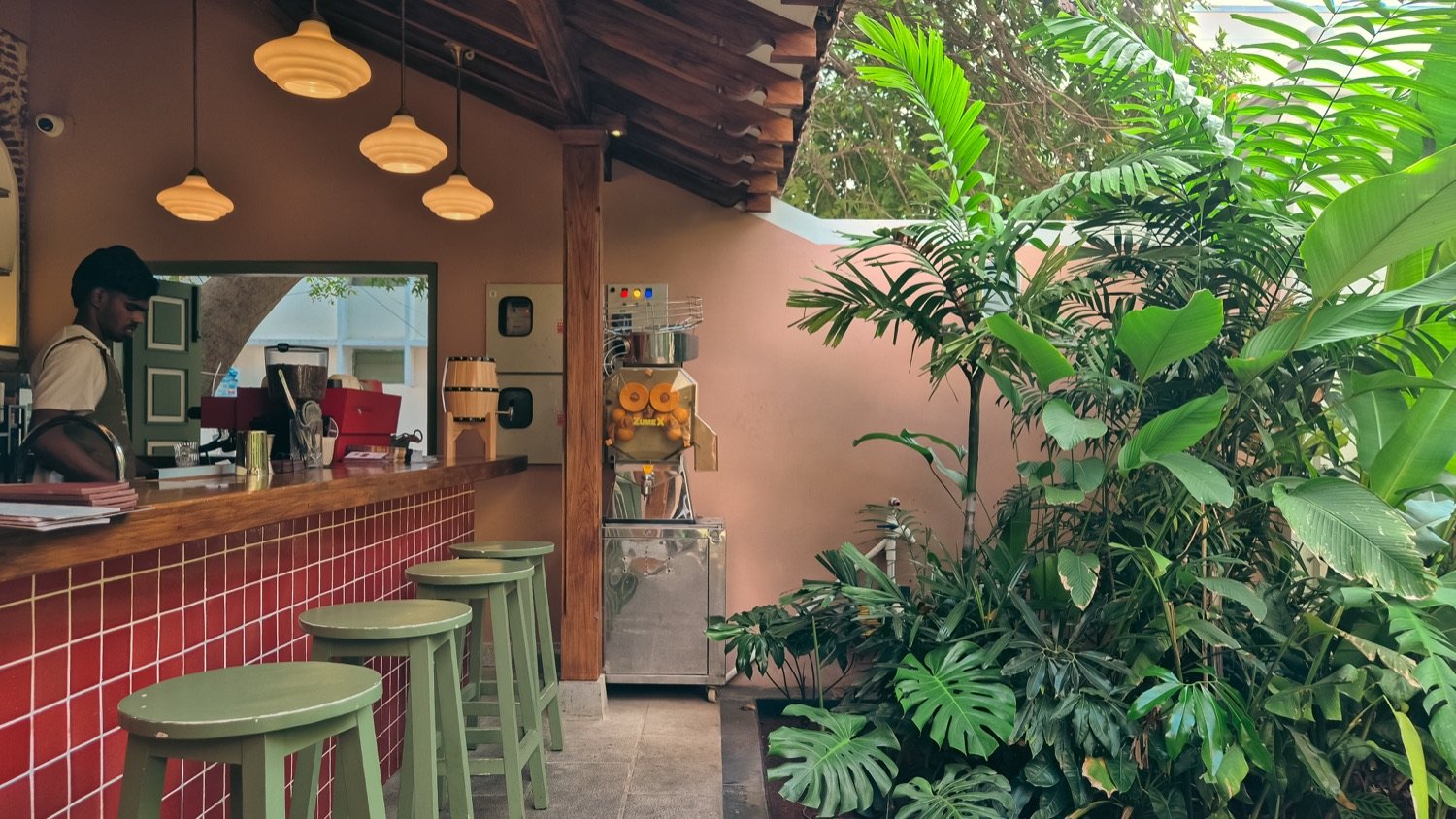 Cherry Pond bar counter in warm red tile with green stools and tropical planting